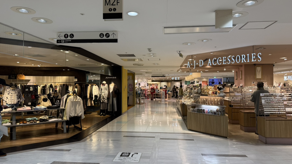 階段を下りると、左手に「JENASIS」さんがございます。「JENASIS」さんを左手に見ながら通路を直進してください。