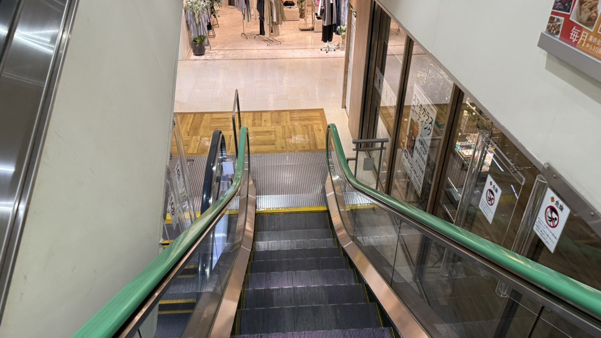 通路左手(JENASISさん奥)のエスカレーターを下り、右手に回ると当店がございます！