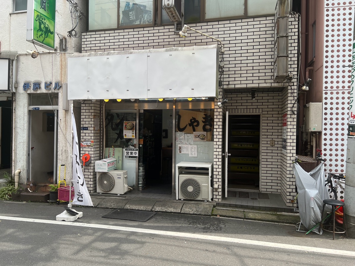 右手のラーメン屋「タンメンしゃきしゃき」の右側にある階段を上りまして3階になります。