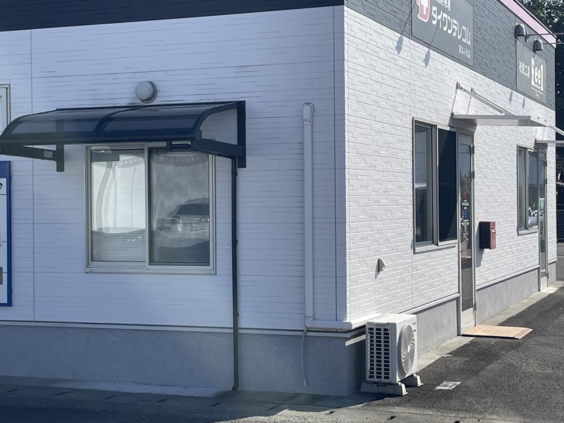 駐車場中央奥にある建物（ダイワンテレコム熊本八代店）にお入りください。